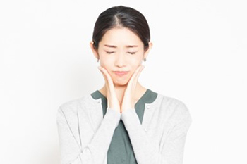 頬をおさえる女性